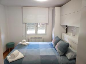 Un dormitorio con una cama azul y una ventana en Duplex a 25 metros de la playa, en Somo
