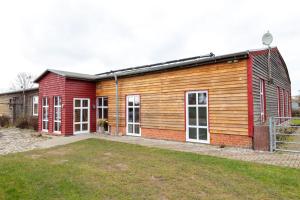 a red and wooden building with a yard at Quartier Penne-Projekthaus in Krummenhagen