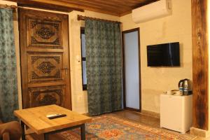 uma sala de estar com uma porta, uma mesa e uma televisão em Kayra Cave Suites em Goreme