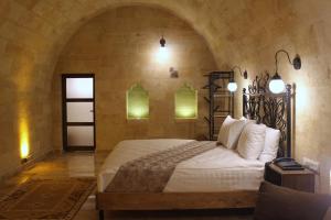 a bedroom with a large bed in a stone wall at Kayra Cave Suites in Göreme
