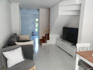 ein Wohnzimmer mit einem Sofa und einem TV in der Unterkunft Duplex a 25 metros de la playa in Somo