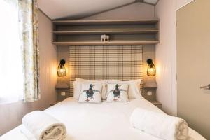 a bedroom with a bed with two ducks on the pillows at Yew Tree Lodge with Hot Tub in York