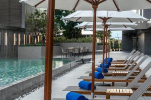 巴吞他尼的住宿－诺富特曼谷兰实未来公园酒店，游泳池旁的一排椅子和遮阳伞