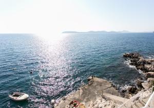 un bateau dans l'eau à côté d'une rive rocheuse dans l'établissement Apartments Neve, à Dubrovnik