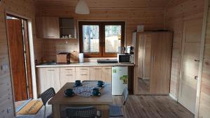 a kitchen with a table and a white refrigerator at Zakątek Borsk, Jasnochówka 2, domek 37 in Borsk