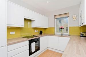 a kitchen with white cabinets and a window at Charming Old Town 2 Bed Apt, 2mins from Royal Mile in Edinburgh