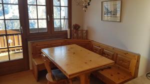 einen Holztisch und Stühle in einem Zimmer mit Fenstern in der Unterkunft Ferienwohnung Silberdistel in Bellwald