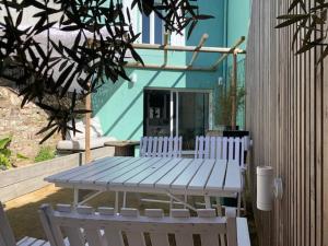 una mesa de picnic y dos sillas blancas frente a una casa en DU MANN petite maison jardin à 100m du port de Vannes avec PARKING, en Vannes