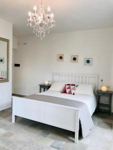 Un dormitorio con una gran cama blanca y una lámpara de araña. en Almasarda en Olbia