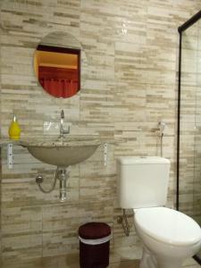 a bathroom with a toilet and a sink and a mirror at Pousada Canto Verde in Paraty