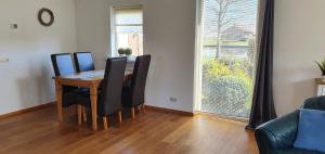 a dining room table with black chairs and a large window at Vakantiehuis de wilgenhof in Wetering +13 photos