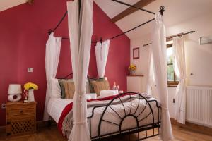 een slaapkamer met een hemelbed met rode muren bij Beautiful Countryside cottage on the North Wales Coast in Abergele