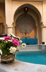 un jarrón lleno de flores sentado junto a una piscina en Riad Papillon by Marrakech Riad, en Marrakech