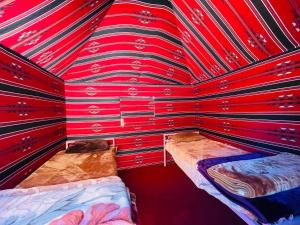 una habitación de paredes rojas con 2 camas. en Bedouin host camp& with tour, en Wadi Rum