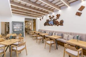 un restaurante con mesas de madera y un sofá en Hotel S'Antiga Adults Only en Es Mercadal