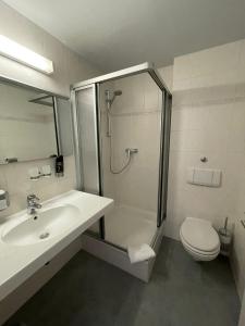 ein Bad mit einer Dusche, einem Waschbecken und einem WC in der Unterkunft Hotel Berlin in Leipzig