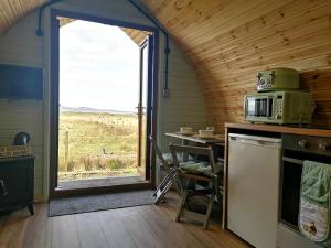 Halkirk的住宿－Achmeney Glamping Pod Larger than Average Pod，厨房配有微波炉、桌子和窗户。