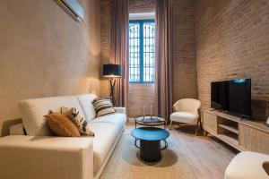 a living room with a white couch and a tv at La Sillería de Triana by Magno Apartments in Seville