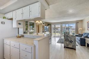 a kitchen with white cabinets and a living room at Sandpiper Cove 1082 Destin Condo in Destin