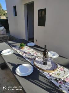 a table with plates and a bottle of wine on it at Kuća za odmor MANA in Lun