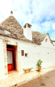 een wit gebouw met een rode deur en een cactus bij Trulli Antica Fonte Luxury Suite in Alberobello