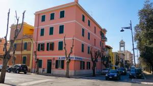 a pink building on a street with a clock tower at Lighthouse Ladispoli al mare in Ladispoli