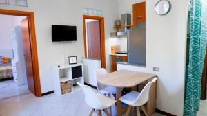 a kitchen with a wooden table and white chairs at Lighthouse Ladispoli al mare in Ladispoli +25 photos