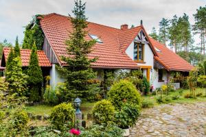 ein Haus mit einem roten Dach und einem Garten in der Unterkunft Leśna Zagroda in Parchowo