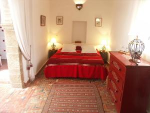 a bed room with a red couch and red pillows at Dar Ness in Essaouira