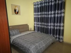 a small bedroom with a bed and a curtain at Lovely 3-bedroom house with beautiful compound in Kumasi