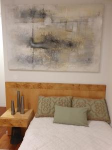 Un dormitorio con una cama con una pintura encima. en Senhora da Guia Boutique Apartment en Vila do Conde