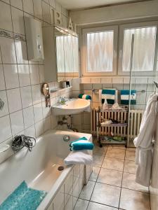 ein Badezimmer mit einer Badewanne und einem Waschbecken in der Unterkunft Apartment Orchidee in Mülheim an der Ruhr
