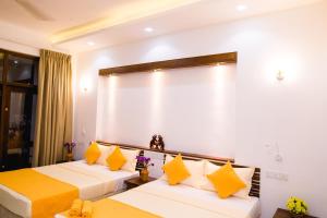 - 2 lits dans une chambre d'hôtel avec des oreillers jaunes dans l'établissement Venus Heaven Luxurious Villa, à Tangalle