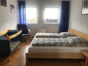 a bedroom with two beds and a chair and two windows at Ferienwohnung "Zwei Birken" in Ellwangen