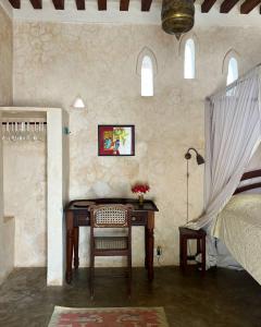 
a room with a bed, table and a window at Subira House in Lamu
