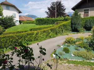 un jardin avec de nombreuses plantes et un chemin dans l'établissement Maison 100m2, espaces verts, 8 min à pied du lac, piste cyclable, à Sévrier
