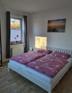 - une chambre avec un lit doté de draps violets et une fenêtre dans l'établissement Kleine Möwe Emden, à Emden