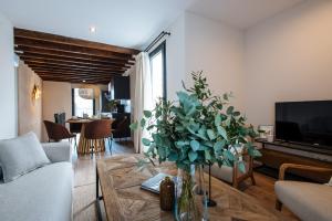 una sala de estar con un jarrón de flores sobre una mesa en La Sillería de Triana by Magno Apartments en Sevilla