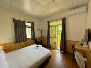 a bedroom with a bed and a tv and a window at Lao Fan Home in An-shuo