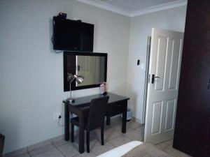 Habitación con escritorio y TV en la pared. en Turn and slip en Bloemfontein
