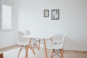 a white dining room with white chairs and a table at Corrientes Premium con desayuno in Bahía Blanca