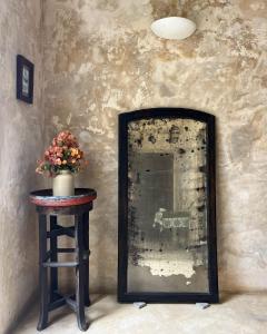 uno specchio seduto su un tavolo accanto a uno sgabello con fiori di Subira House a Lamu