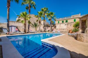 a swimming pool with palm trees and a building at Ideal Property Mallorca - Verdera in Maria de la Salut