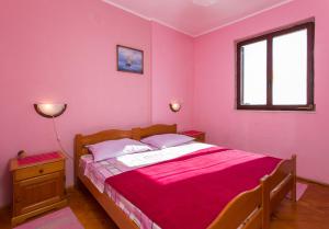 Un dormitorio con una cama con paredes rosas y una ventana en Apartments Neve, en Dubrovnik