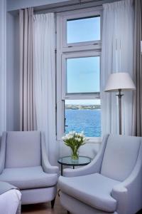 a living room with two chairs and a table and a window at Poseidonion Grand Hotel in Spetses