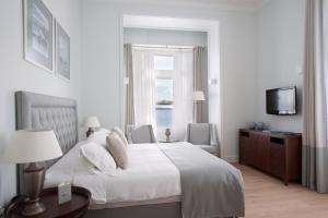 a white bedroom with a bed and a window at Poseidonion Grand Hotel in Spetses