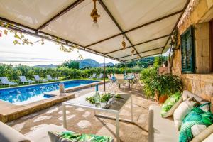 an outdoor patio with a table and a swimming pool at Ideal Property Mallorca - Can Carabassot in Pollença