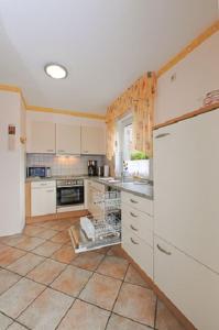 eine Küche mit einem weißen Kühlschrank und Fliesenboden in der Unterkunft Ferienwohnung Riegstra in Esens