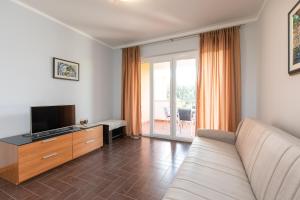 ein Wohnzimmer mit einem Sofa und einem TV in der Unterkunft Apartments Bella Vista in Krk