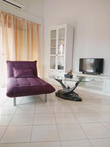 uma sala de estar com um sofá roxo e uma mesa de vidro em Apartmani Nikolina em Ražanac